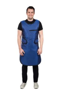 A male radiology technician wears a blue, full-length lead apron, an important radiation protection device for lab staff members.